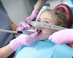 Child breathing in nitrous oxide while dentist examines their teeth