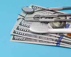 Toothbrush and dental instruments on hundred dollar bills on a blue background