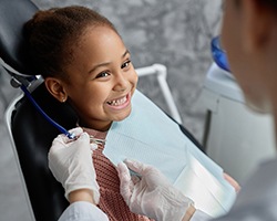 Little girl smiling at dentist after receiving dental sealants