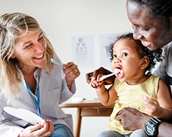 Dentist with parent and baby brushing teeth