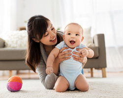 Happy mother and baby playing on floor 